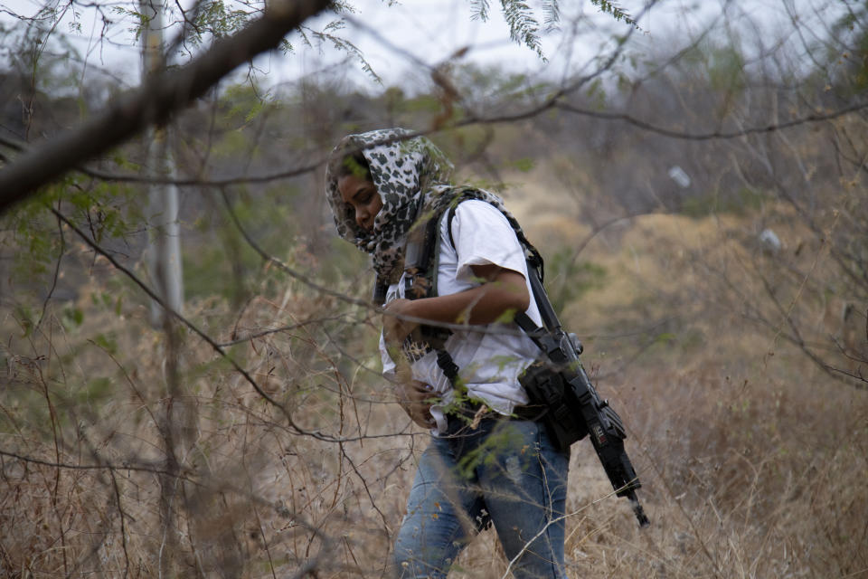 An armed woman who goes by the nickname "La Chola," and who says she is a member of a female-led, self-defense group, patrols the edge of her town of El Terrero, where it shares a border with the town of Aguililla, in Michoacan state, Mexico, Thursday, Jan. 14, 2021. In the birthplace of Mexico’s vigilante “self-defense” movement, a new group has emerged entirely made up of women, who carry assault rifles and post roadblocks to fend off what they say is a bloody incursion into the state of Michoacán by the violent Jalisco cartel. (AP Photo/Armando Solis)