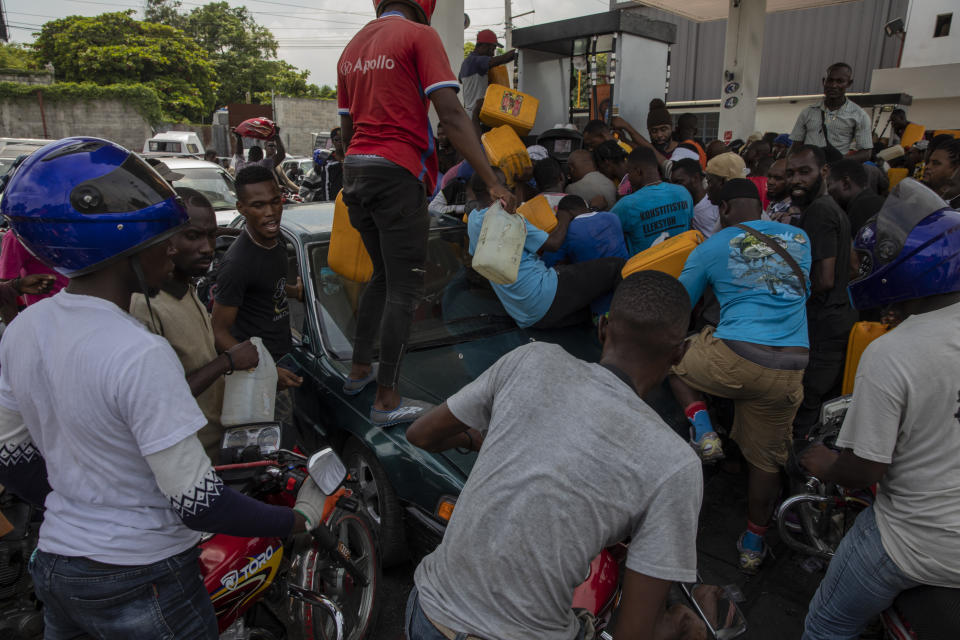 Un grupo de personas se empujan mientras tratan de llenar sus tanques en una gasolinera en Puerto Príncipe, Haití, el 22 de septiembre de 2021. Además de los secuestros, se culpa a las pandillas por bloquear las terminales de distribución de gas y por retener los camiones cisterna, lo que según las autoridades ha generado escasez de gasolina. (AP Foto/Rodrigo Abd)