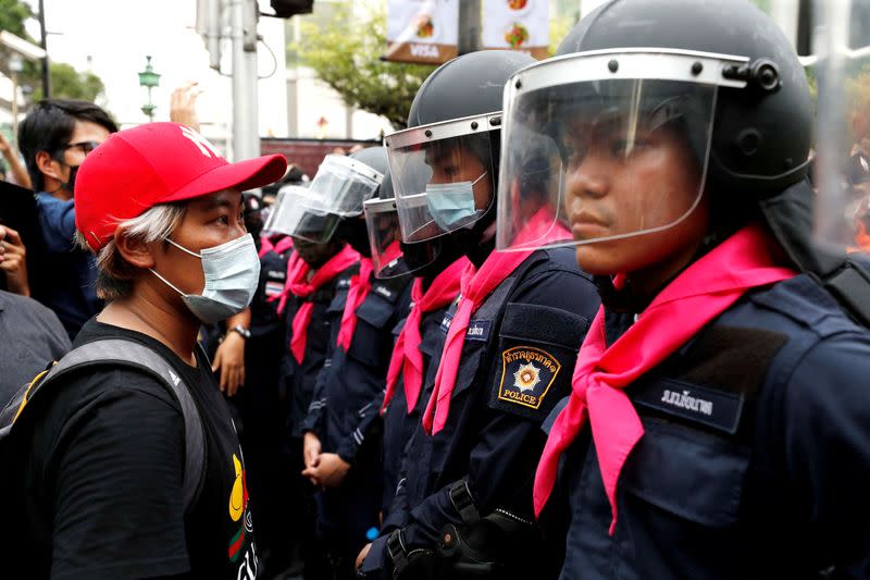 FILE PHOTO: A pro-democracy protester stands in front of police officers during anti-government protests in Bangkok