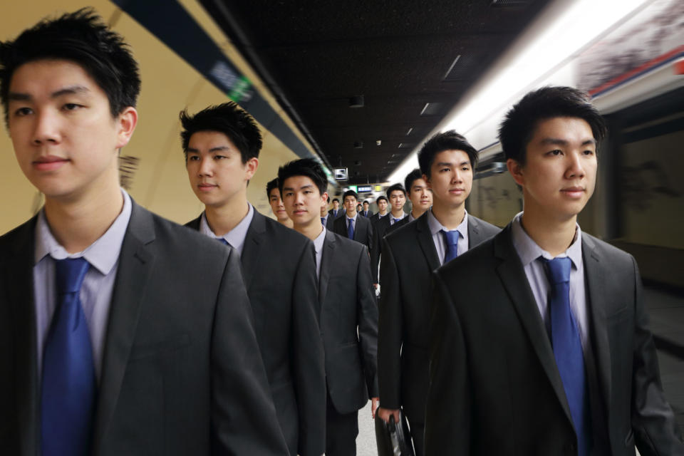 Identical men in suits walking down a subway tunnel