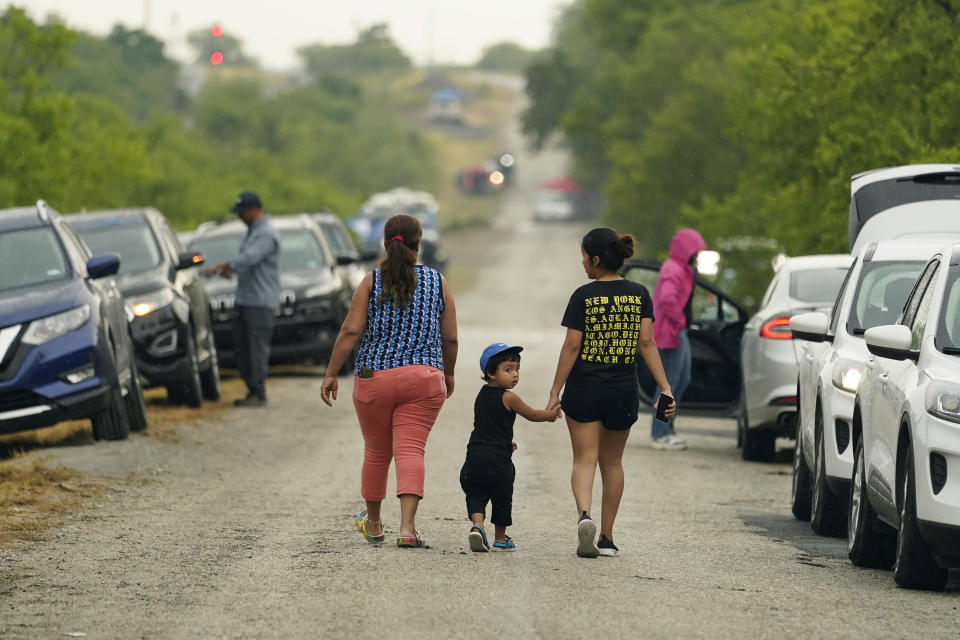 A family walks away after visiting a make-shift memorial at the site where officials found dozens of people dead in a semitrailer containing suspected migrants, Tuesday, June 28, 2022, in San Antonio. (AP Photo/Eric Gay)