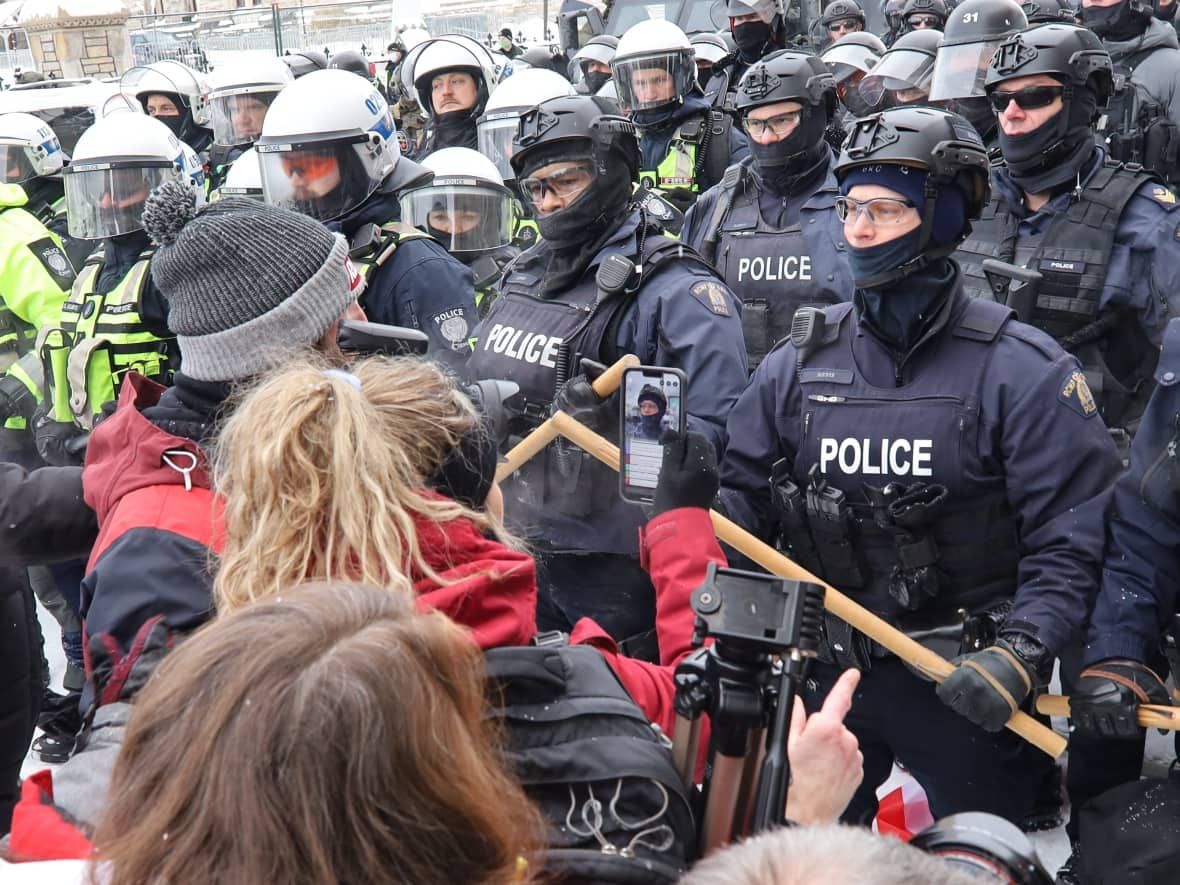 A line of anti-mandate protesters stands face-to-face with a line of police officers in downtown Ottawa on Saturday, Feb. 19, 2022. (Michael Charles Cole/CBC - image credit)