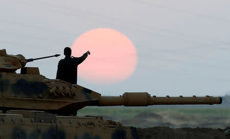 A Turkish soldier points as he stands on a tank during a military exercise near the Turkish-Iraqi border in Silopi, Turkey, September 22, 2017. REUTERS/Umit Bektas