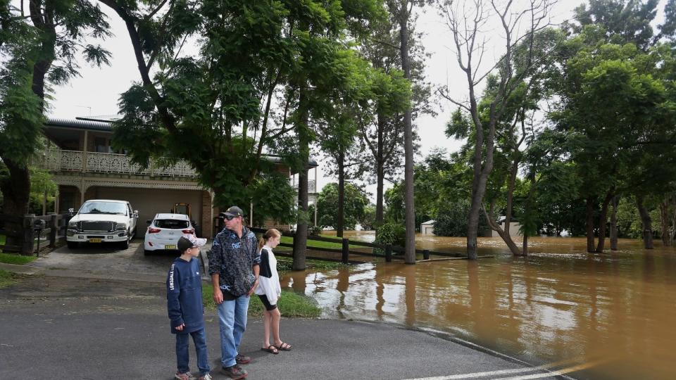 People outside house near flooded road.