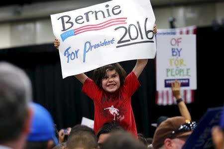 A young boy holds up a sign supporting democratic U.S. presidential candidate Bernie Sanders before a campaign rally in San Diego, California March 22, 2016. REUTERS/Mike Blake