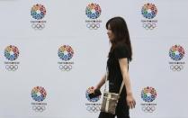 A woman walks past host city logos of the Tokyo 2020 Bid Committee at Tokyo Metropolitan Government Building in Tokyo September 8, 2013. REUTERS/Yuya Shino