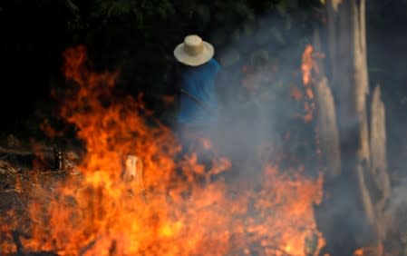 FILE PHOTO: A man works in a burning tract of Amazon jungle as it is being cleared by loggers and farmers in Iranduba