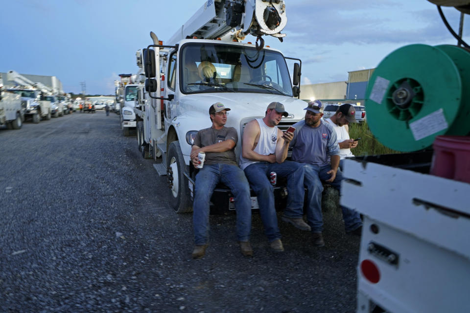 Workers from Southwest Arkansas Electric, of Texarkana, Ark., relax on their truck after a day's work, inside a tent city for electrical workers in Amelia, La., Thursday, Sept. 16, 2021. In the wake of hurricanes, one of the most common and comforting sites is the thousands of electric workers who flow into a battered region when the winds die down to restore power and a sense of normalcy. (AP Photo/Gerald Herbert)