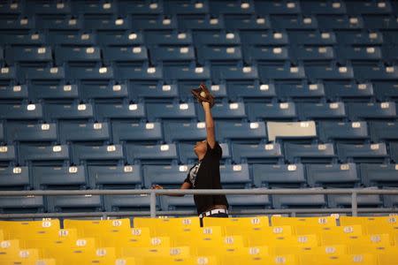 A boy plays with a ball and glove during a baseball game between Los Maceteros de Vega Alta and Los Atenienses de Manati during the Puerto Rico Double A baseball league at Manati, Puerto Rico, June 6, 2016. REUTERS/Alvin Baez