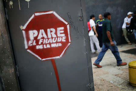 People walk past a graffitti that reads "Stop the fraud of the MUD" in Caracas, Venezuela February 6, 2017. REUTERS/Marco Bello