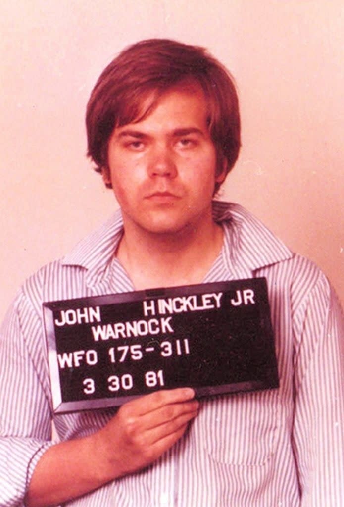 Mugshot of Hinckley holding a nameplate with identifying information