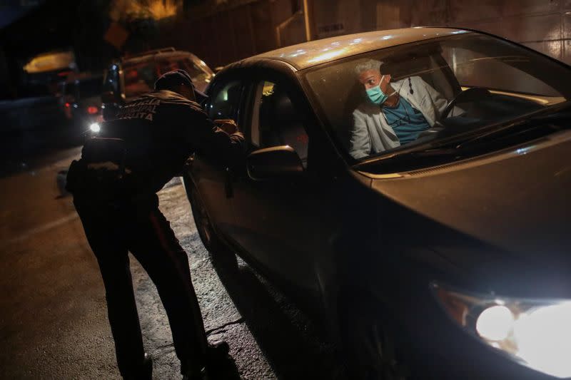 Doctor Carlos Martinez speaks with a police officer while in line to get fuel at a gas station, during a nationwide quarantine due to the coronavirus disease (COVID-19) outbreak, in Caracas