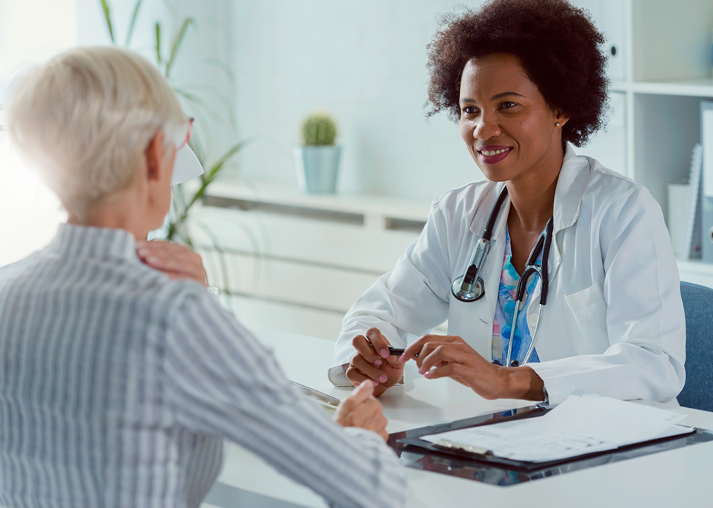 Patient speaking to doctor, both sitting at a desk.