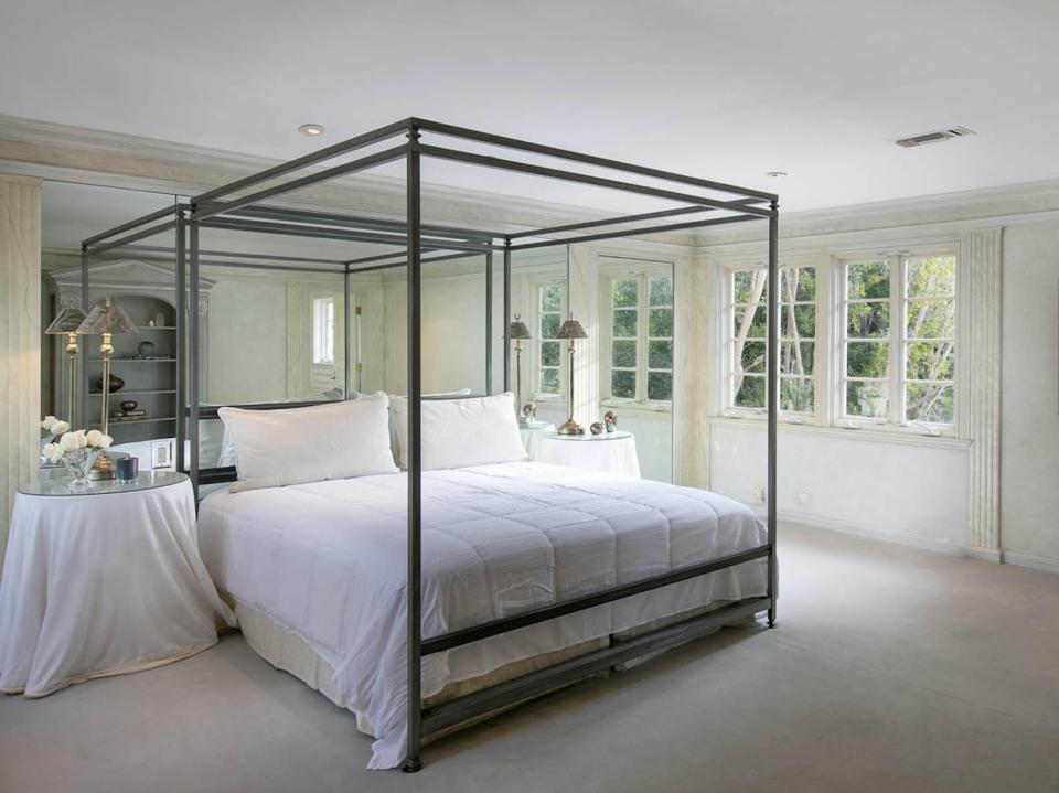 a bedroom with a bed in front of a mirrored wall