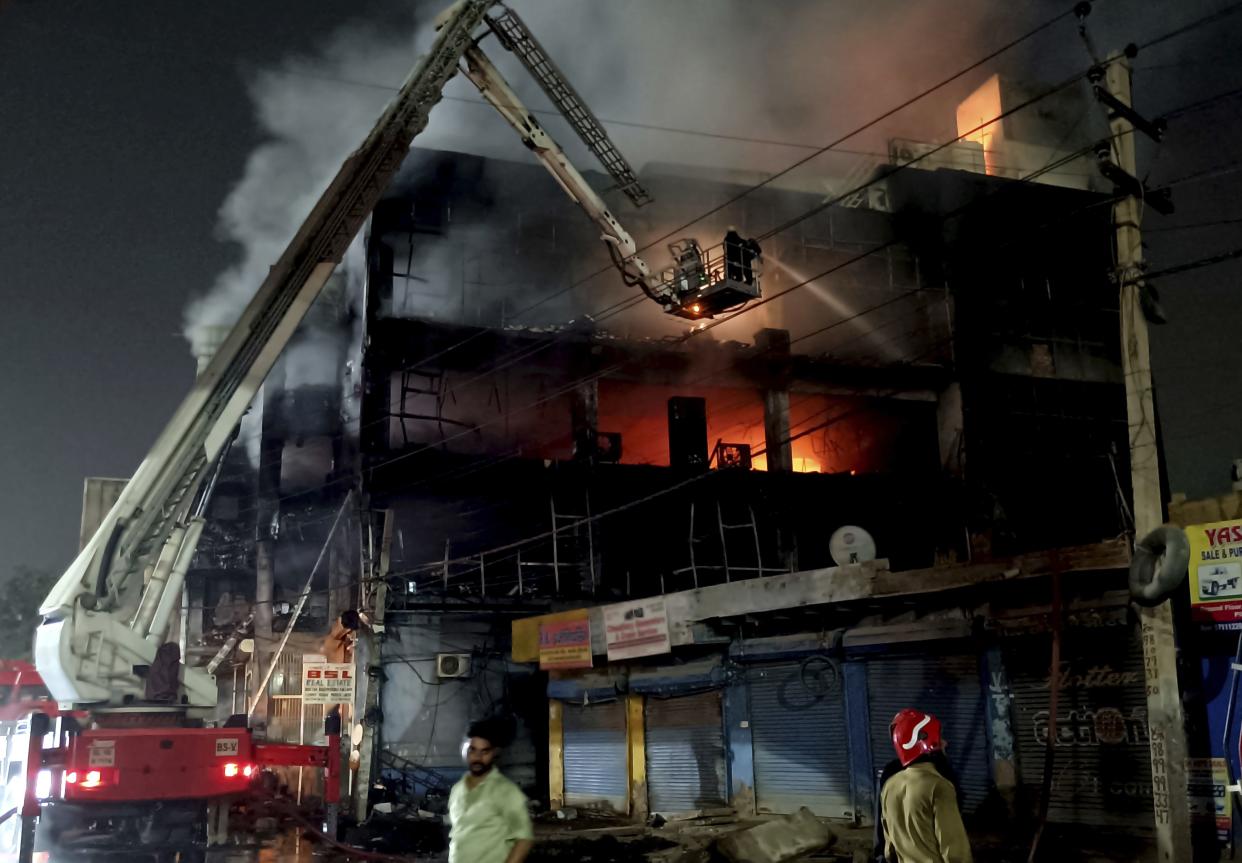Fire officials try to douse a fire in a four storied building, in New Delhi, India, on Friday.