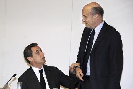 Nicolas Sarkozy (L) head of the French conservative UMP political party, holds the arm of French politician Alain Juppe (R), former prime minister and Mayor of Bordeaux, prior to a meeting at their party headquarters in Paris December 3, 2014. REUTERS/Dominique Faget/Pool