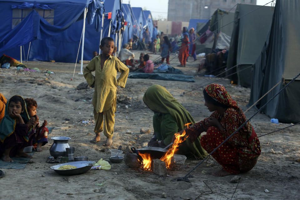 Victims of heavy flooding from monsoon rains take refuge as they prepare tea at a temporary tent housing camp organized by the UN Refugee Agency (UNHCR), in Sukkur, Pakistan, Saturday, Sept. 10, 2022. Months of heavy monsoon rains and flooding have killed over a 1000 people and affected 3.3 million in this South Asian nation while half a million people have become homeless. (AP Photo/Fareed Khan)