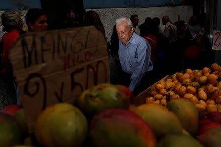A man walks past people queueing to try and buy food outside a supermarket in Caracas, Venezuela May 23, 2016. REUTERS/Carlos Garcia Rawlins