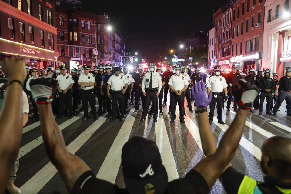 Protesters take a knee on Flatbush Avenue in front of New York City police officers during a solidarity rally for George Floyd, Thursday, June 4, 2020, in the Brooklyn borough of New York. Floyd died after being restrained by Minneapolis police officers on May 25. (AP Photo/Frank Franklin II)