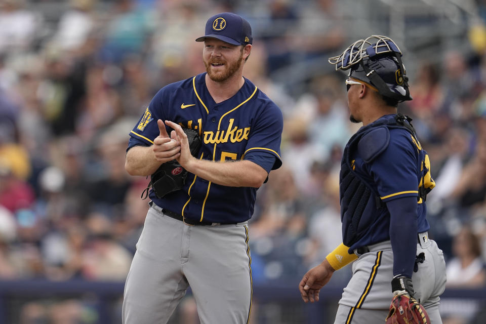 Milwaukee Brewers starting pitcher Brandon Woodruff, left, and catcher William Contreras talk after a solo home run by Seattle Mariners' Cooper Hummel during the third inning of a spring training baseball game, Monday, March 20, 2023, in Peoria, Ariz. (AP Photo/Abbie Parr)