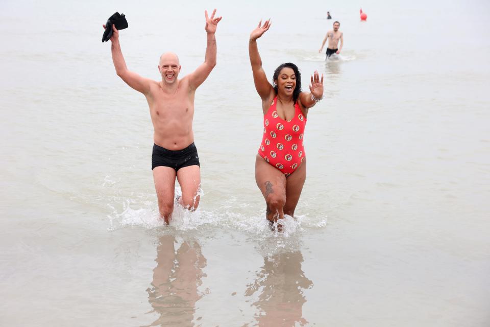 Tokara Henry in a red swimsuit, celebrates the plunge with a friend on Monday, January 1, 2024 plungers rang in the the New Year with a splash at the annual Polar Bear Plunge at Bradford Beach in Milwaukee, Wisconsin.