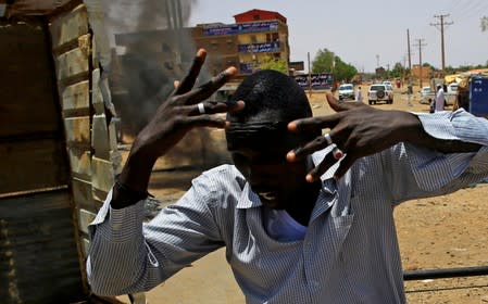 A Sudanese protester gestures as he runs past a barricade along a street, demanding that the country's Transitional Military Council hand over power to civilians, in Khartoum