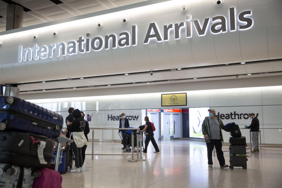 Passengers wearing face masks arrive on the first day of new rules that people arriving in Britain from overseas will have to quarantine themselves for 14 days to help stop the spread of coronavirus, at Heathrow Airport in London, Monday, June 8, 2020. The British government has said that anyone caught not complying with the quarantine will face a fine. (AP Photo/Matt Dunham)