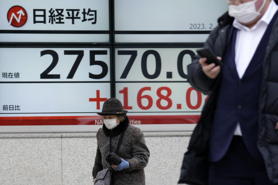 People wearing a protective mask walk in front of an electronic stock board showing Japan's Nikkei 225 index at a securities firm Friday, Feb. 3, 2023, in Tokyo. Asian shares were trading mixed Friday ahead of a closely watched U.S. jobs report that may affect global interest rates. (AP Photo/Eugene Hoshiko)