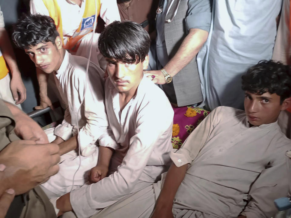 Youngsters, left, who were trapped in a broken cable car, are surrounded by villagers following their rescue, in Pashto village, a mountainous area of Battagram district in Pakistan's Khyber Pakhtunkhwa province, late Tuesday, Aug. 22, 2023. Army commandos using helicopters and a makeshift chairlift rescued eight people from a broken cable car dangling hundreds of meters (feet) above a canyon Tuesday in a remote part of Pakistan, authorities said. (AP Photo/Nasir Mahmood)