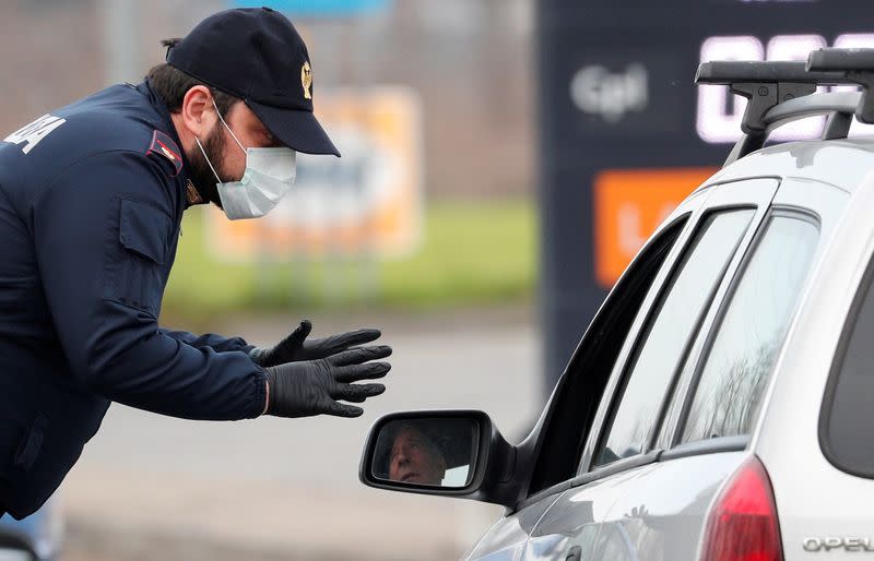 FILE PHOTO: A policeman wearing a face mask warns a driver on the road between Codogno and Casalpusterlengo, which has been closed by the Italian government due to a coronavirus outbreak in northern Italy