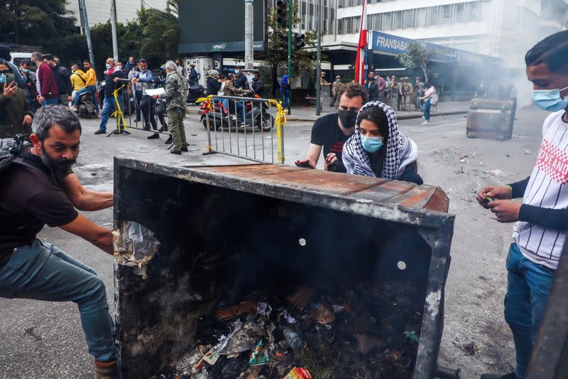 Demonstrators push a garbage bin along a blocked road during a protest in Beirut