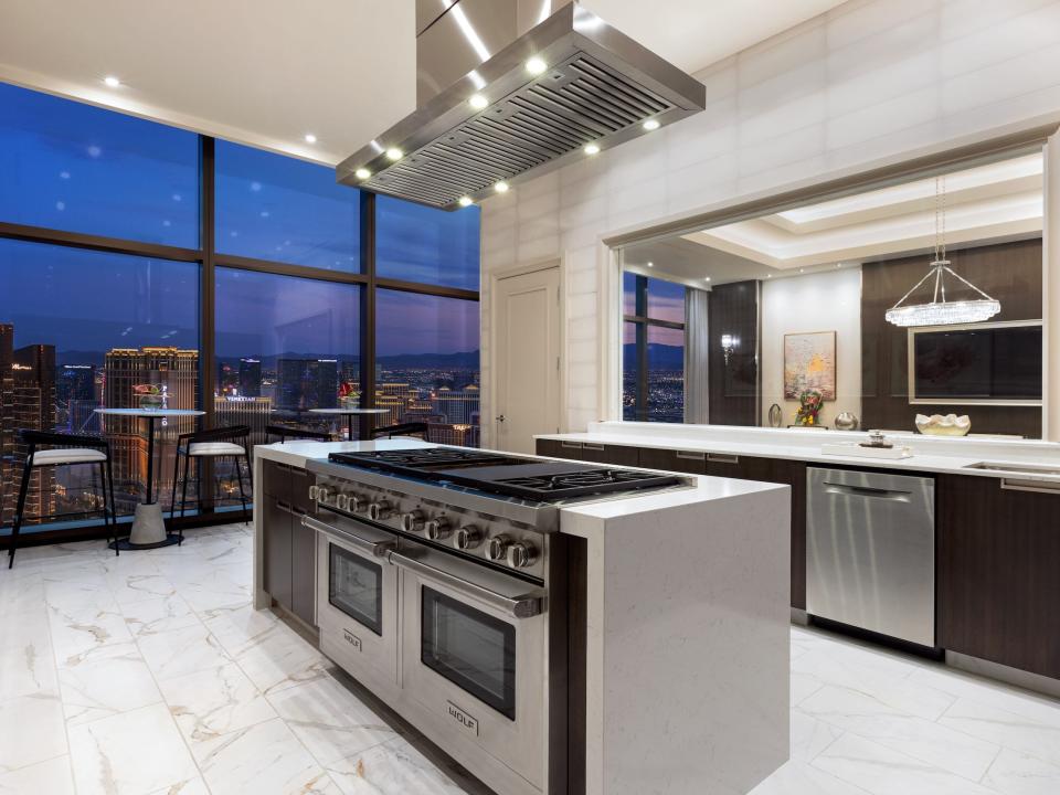 a modern kitchen with an island next to a large floor to ceiling window with views of Las Vegas