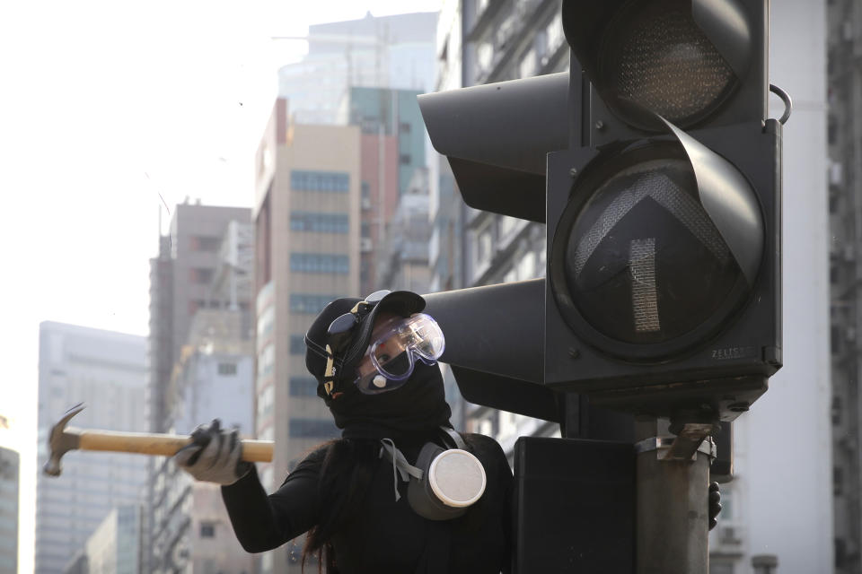 In this Thursday, Nov. 14, 2019, file photo, a protester smashes a streetlight near Hong Kong Polytechnic University in Hong Kong. Protesters who barricaded themselves inside Hong Kong’s universities have tried to turn the campuses into armed camps, resorting to medieval weapons to stop police from entering the grounds. Their weapons include bows and arrows, catapults and hundreds of gasoline bombs stacked up to ramparts - often built by the students. (AP Photo/Kin Cheung, File)