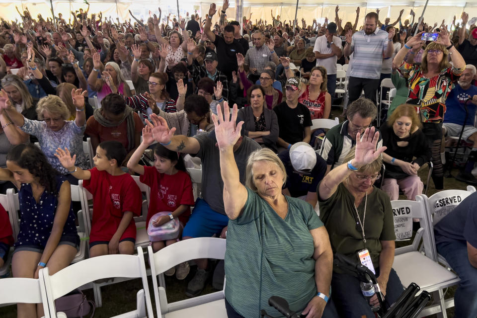 Attendees raise their hands as they worship inside the tent during the ReAwaken America tour at Cornerstone Church, in Batavia, N.Y., Friday, Aug. 12, 2022. Speaking at the event, Michael Flynn, former national security adviser to former President Donald Trump, is trying to build a movement centered on Christian nationalist ideas, where Christianity is at the center of American life and institutions. (AP Photo/Carolyn Kaster)