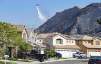 A helicopter drops water onto hot spots of the Silverado Fire behind homes in the Foothill Ranch area near Lake Forest, Calif., Wednesday, Oct. 28, 2020. (Mark Rightmire/The Orange County Register via AP)