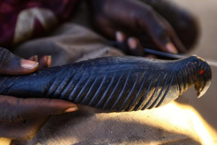 A man crafts a figurine from ebony tree at the Gabe Bazaar in Khartoum, Sudan on November 5, 2022. Craftsmen of Southern Sudan make various objects with ebony tree, known for its durability.