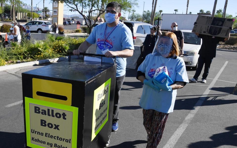 Workers place a ballot box for dropping off mail-in ballots next to a tent being used as an early voting polling location - Ethan Miller/Getty Images