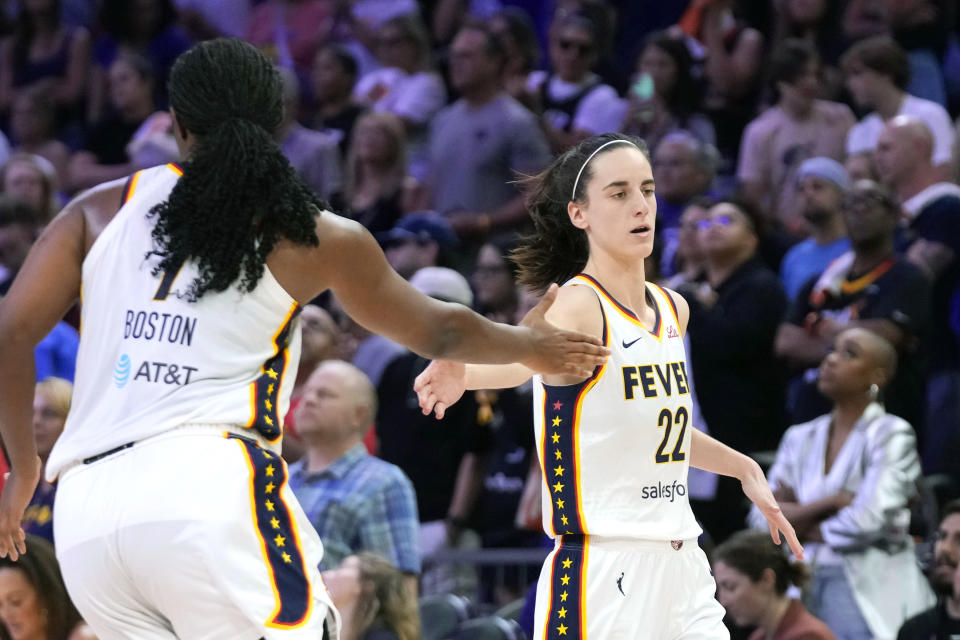 Indiana Fever guard Caitlin Clark (22) slaps hands with Fever forward Aliyah Boston, left, after a assisting against the Phoenix Mercury during the second half of a WNBA basketball game Sunday, June 30, 2024, in Phoenix. (AP Photo/Ross D. Franklin)