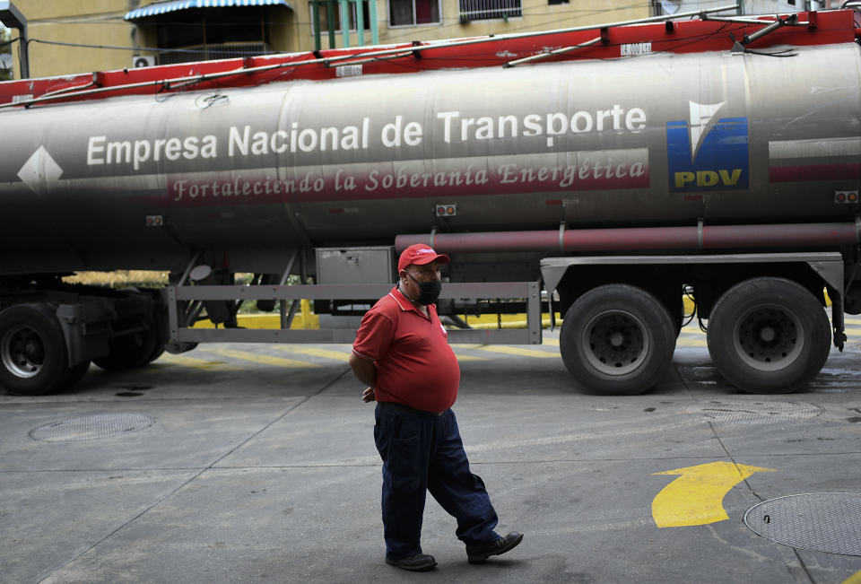 A worker wearing a face mask amid the new coronavirus pandemic waits while a tanker truck supplies gasoline to a state oil company gas station in Caracas, Venezuela, Sunday, May 31, 2020. After decades of being the cheapest gasoline in the world, Venezuelan President Nicolas Maduro indicates that as of next Monday a new pricing scheme will be imposed on some 200 stations. (AP Photo/Matias Delacroix)