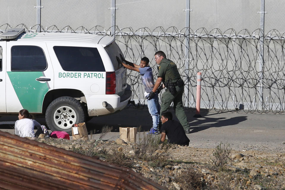 FILE - In this Dec. 15, 2018, file photo, Honduran asylum seekers are taken into custody by U.S. Border Patrol agents after the group crossed the U.S. border wall into San Diego, Calif., seen from Tijuana, Mexico. Detained asylum seekers who have shown they have a credible fear of returning to their country will no longer be able to ask a judge to grant them bond. U.S. Attorney General William Barr decided Tuesday, April 16, 2019, that asylum seekers who clear a "credible fear" interview and are facing removal don't have the right to be released on bond while their cases are pending and will have to wait in detention until their case is adjudicated. (AP Photo/Moises Castillo, File)