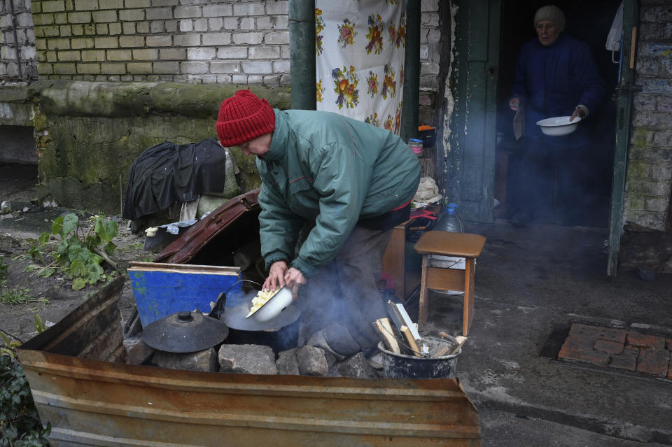 Ancianas cocinan en una hoguera en el patio de un edificio de apartamentos en Lyman, en la región de Donetsk, Ucrania, el domingo 20 de noviembre de 2022. La situación en Kiev y otras grandes ciudades ucranianas ha empeorado de forma drástica tras los últimos ataques de misiles a la red eléctrica. (AP Foto/Andriy Andriyenko)