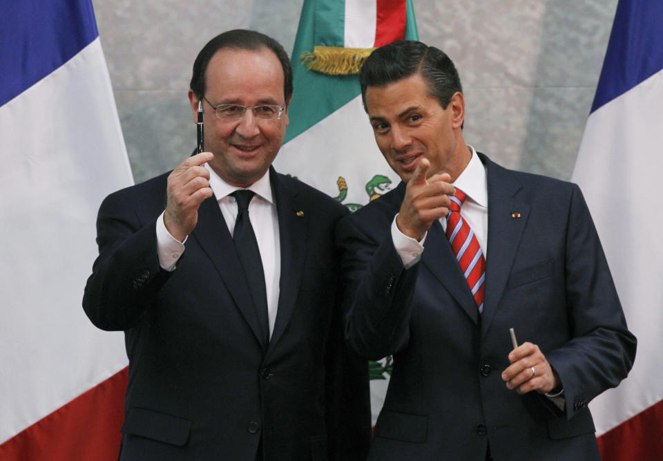 French President Francois Hollande, left, holds up a pen as Mexico's President Enrique Pena Nieto jokes with a pool of photographers during a bi-lateral signing ceremony at Los Pinos presidential residence in Mexico City, Thursday, April 10, 2014. Hollande is in Mexico for a two-day visit. (AP Photo/Marco Ugarte)