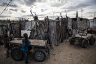 A Palestinian woman stands next to her house in a slum on the outskirts of Khan Younis Refugee Camp, in the southern Gaza Strip, Wednesday, Nov. 25, 2020. Israel's blockade of the Hamas-ruled Gaza Strip has cost the seaside territory as much as $16.7 billion in economic losses and caused its poverty and unemployment rates to skyrocket, a U.N. report said Wednesday, as it called on Israel to lift the 13-year closure. (AP Photo/Khalil Hamra)