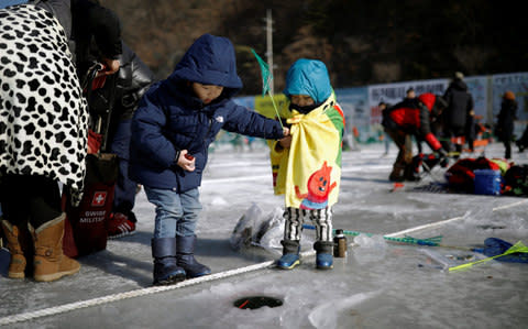 Children fish for trout on a frozen river during the Ice Festival in Hwacheon, south of the demilitarized zone (DMZ) separating the two Koreas - Credit: REUTERS/Kim Hong-Ji
