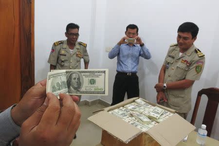 Police and court officials examine notes from a seized haul of $7.16 million in counterfeit hundred-dollar bills, in Battambang September 30, 2014. REUTERS/Andrew RC Marshall