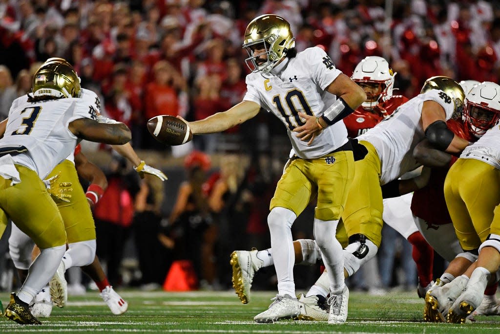 Notre Dame quarterback Sam Hartman (10) hands off the ball to running back Gi'Bran Payne (3) during the second half of an NCAA college football game against Louisville in Louisville, Ky., Saturday, Oct. 7, 2023. (AP Photo/Timothy D. Easley)