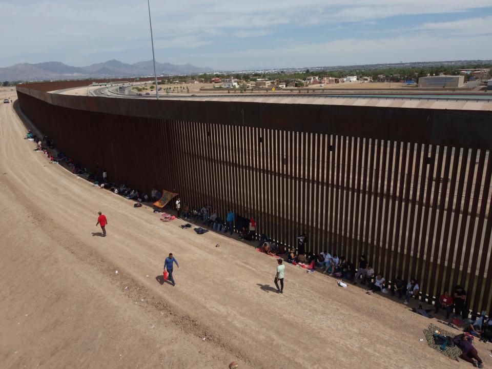 Migrants camp out next to the border barrier between El Paso, Texas and Ciudad Juárez, Mexico, Wednesday, May 3, 2023. The Biden administration has requested 1,500 troops for the U.S.-Mexico border amid an expected migrant surge following the end of pandemic-era restrictions. (AP Photo/Christian Chavez)