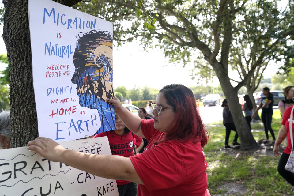 Cynthia Moreno, que se beneficia de un programa de alivio migratorio para jóvenes inmigrantes, cuelga un cartel frente a las Oficinas de Inmigración y Control de Aduanas en Miramar, Florida, el miércoles 15 de junio de 2022. (AP Photo/Lynne Sladky)
