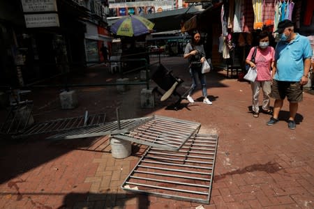 People walk past fallen barricades left from yesterday's protests in Tsuen Wan, Hong Kong