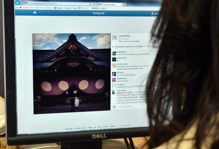 A woman looks at a picture of Japanese Yasukuni shrine posted on the Instagram account of Canadian pop singer Justin Bieber after his visit to the controversial shrine in Tokyo on April 23, 2014